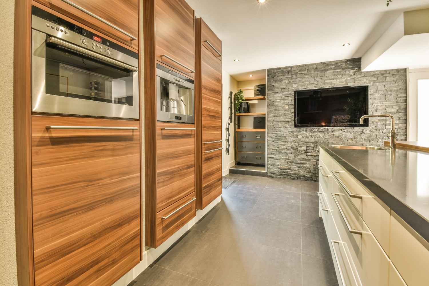 Interior of light kitchen with modern cupboards and appliances located near dining room in modern flat at daytime